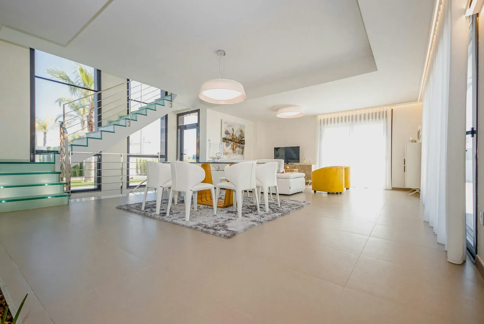 Geniş pencereli, merdivenli aydınlık bir villa salonu